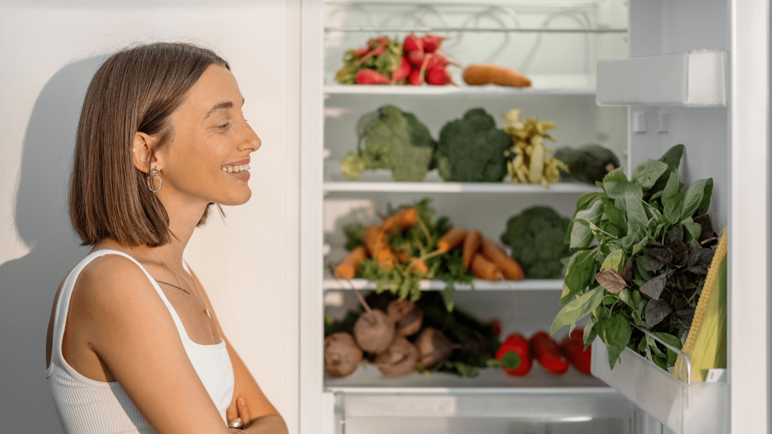 a woman looking at fresh produce in her fridge