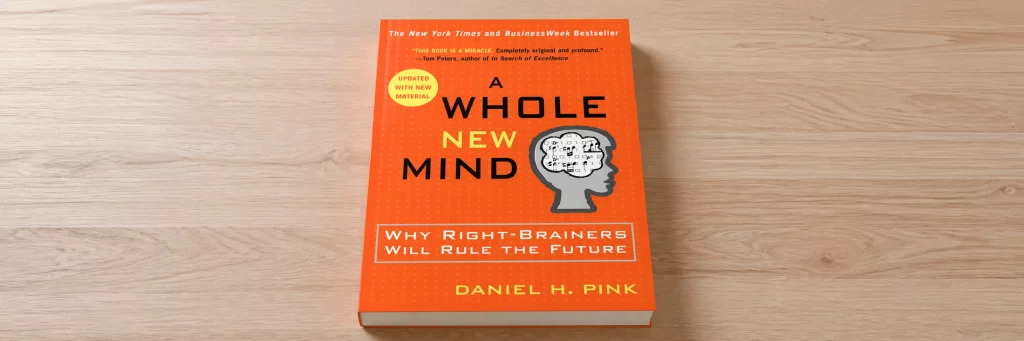 The book "A Whole New Mind" sitting on a wood surface.