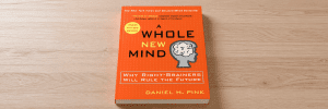 The book "A Whole New Mind" sitting on a wood surface.