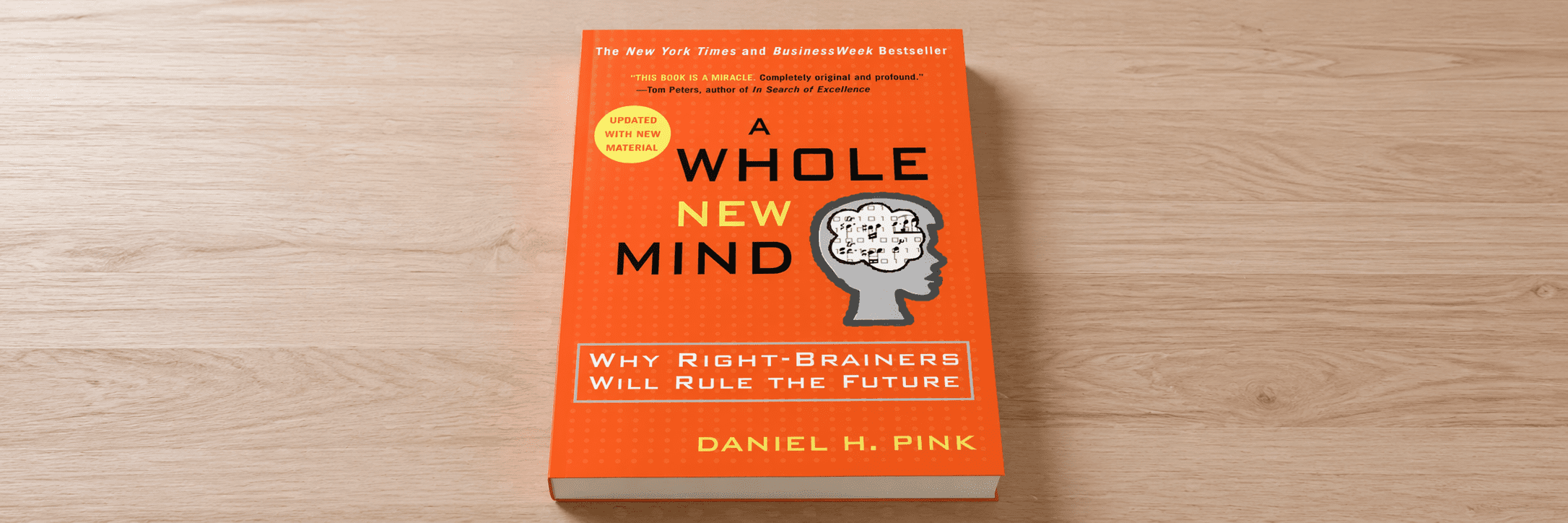 The book "A Whole New Mind" sitting on a wood surface.