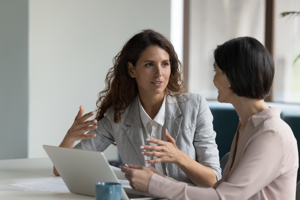 Two professionals practicing mentor skills during a workplace mentoring meeting