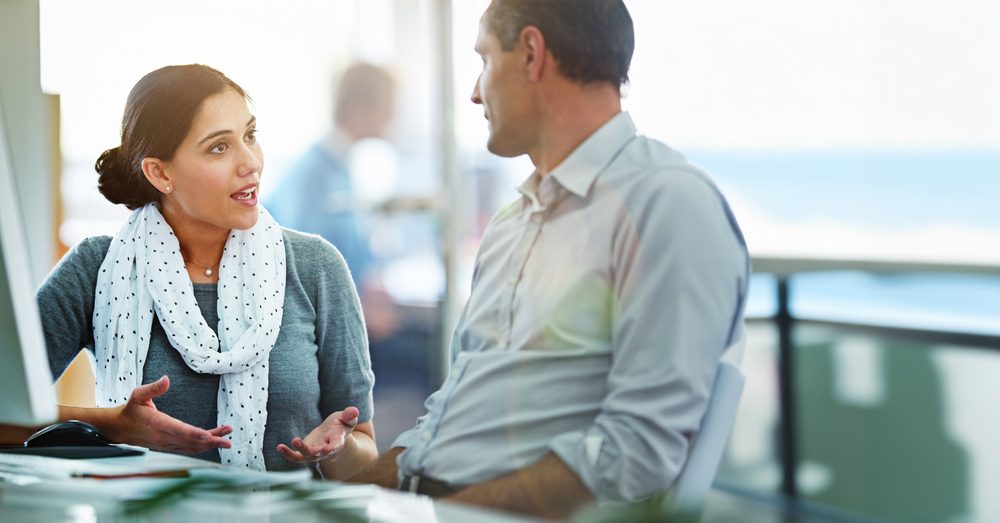 Two professionals discussing talent retention strategies during a one-on-one mentoring conversation in a bright office