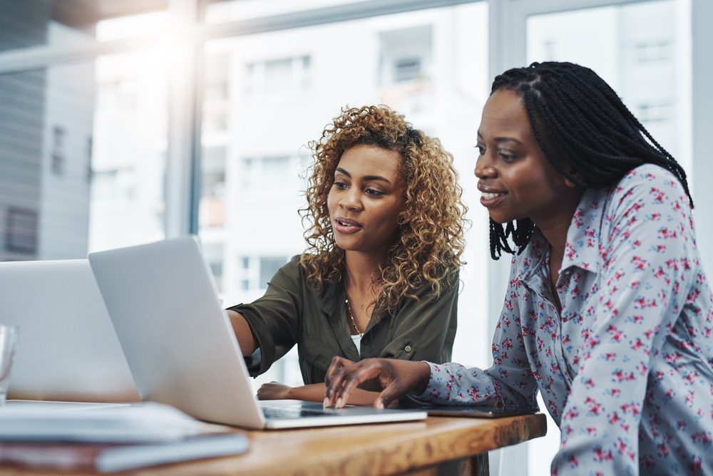 Colleagues smiling and connecting at work, showing the human side of talent retention strategies built on mentoring
