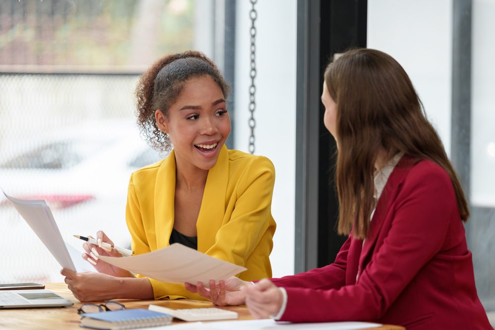 Experienced mentor talking with an emerging leader during a leadership mentoring session at a shared office table