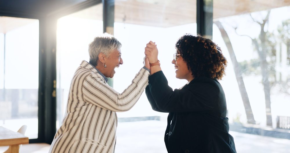 Mentor and mentee shaking hands after a final check in that closes out a well planned mentoring program structure