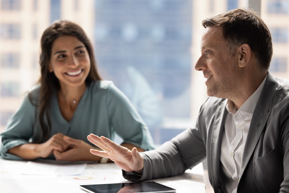 Mentor and mentee discussing talent development strategies across a table in a bright office meeting room